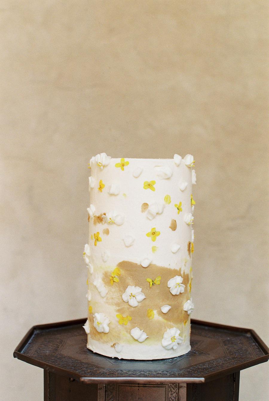 The wedding cake was tall, in white and mustard and with sugar blooms