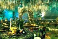 14 an enchanted forest recreated inside with lots of greenery, lights and greenery hanging down and green light
