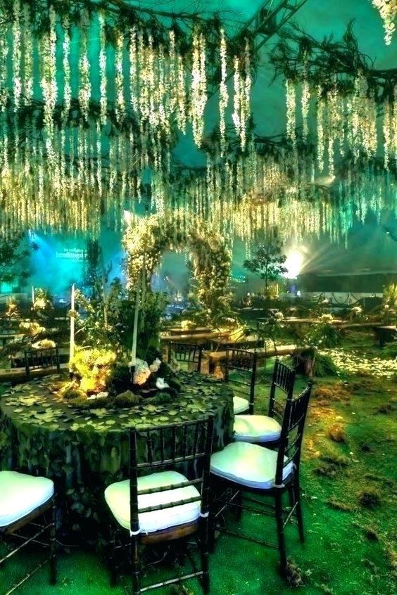 an enchanted forest recreated inside with lots of greenery, lights and greenery hanging down and green light