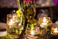 15 an enchanted forest wedding centerpiece with candles wrapped with vine and moss and some vines with blooms next to them