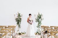 21 a stylish modern meets rustic wedding aisle with greenery, candles and chairs accented with elegant white ribbon bows