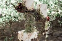 25 an enchanted forest wedding cake arrangement with a tree stump and a greenery holder with nests with two wedding cakes and lots of blooms and greenery