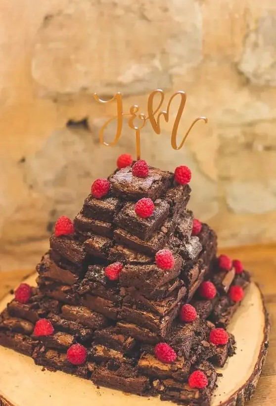 a brownie wedding cake topped with fresh raspberries and with a gold calligraphy cake topper is a sophisticated solution