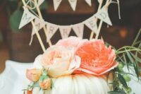 a bundt wedding cake with peachy and orange blooms, greenery and a lovely banner topper for a summer wedding