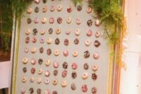 a chic framed donut wall with lush greenery and blooms looks liek a tasty artwork