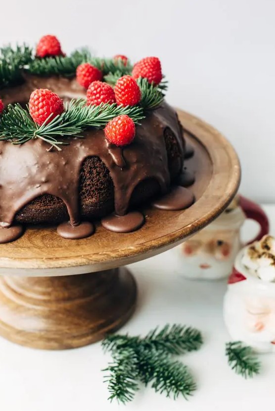 a chocolate wreath wedding cake with chocolate drip, evergreens and raspberries for a Christmas wedding