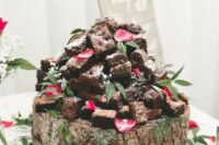 a large tree slice with brownies, pink flower petals, baby’s breath and greenery on top is a cool idea for a rustic wedding