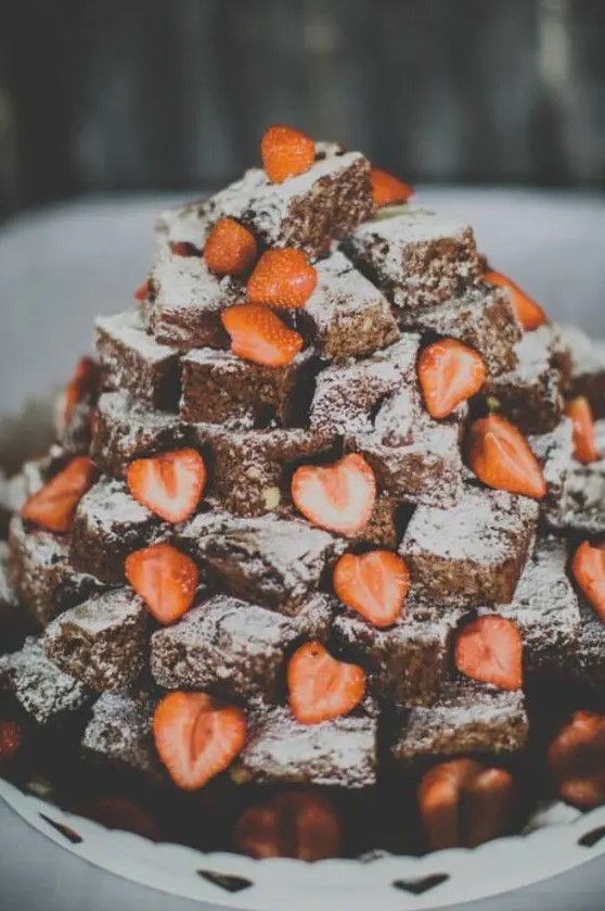 a lovely brownie stack topped with sugar powder and fresh strawberries is a cute idea that looks delicious