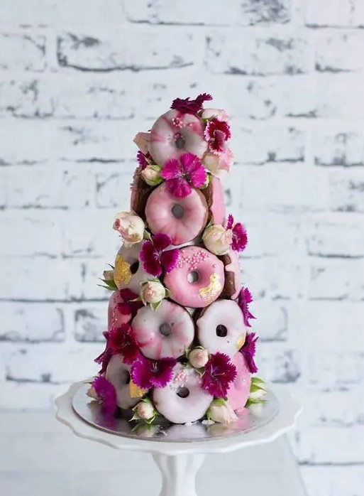 a lovely, cute and whimsy pink glazed donut mini wedding cake decorated with yellow and fuchsia blooms for a bold wedding