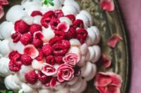 a meringue wedding cake topped with pink roses and fresh raspberries is a stylish idea for a summer wedding, it looks amazing