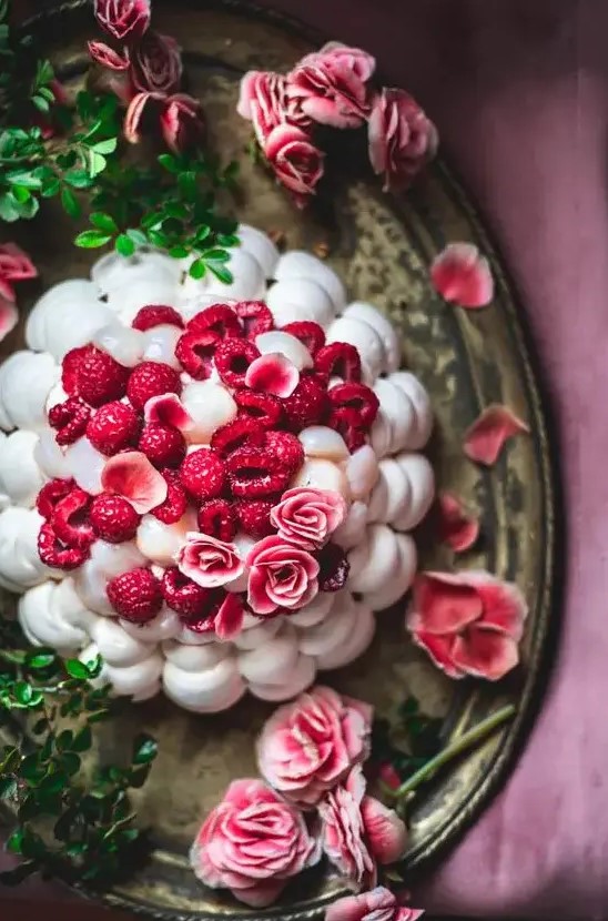 a meringue wedding cake topped with pink roses and fresh raspberries is a stylish idea for a summer wedding, it looks amazing