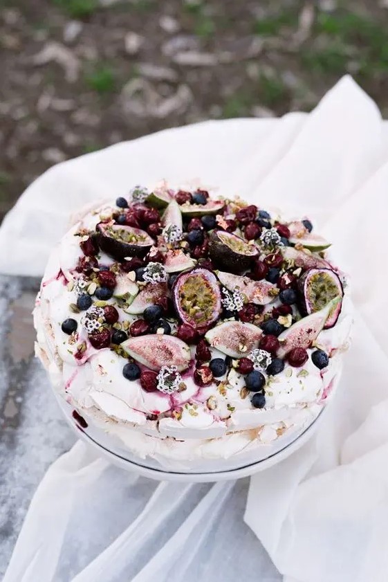 a pavlova wedding cake topped with fresh figs, berries and litle blooms and with berry drip is amazing for a summer wedding