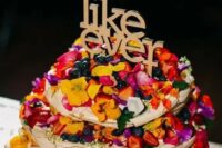 a pavlova wedding cake with colorful petals, bright berries and a letter topper is a lovely idea for a bright boho wedding