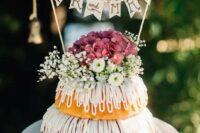 a relaxed two-tier bundt wedding cake with creamy drip, baby’s breath and mauve hydrangeas and a banner topper