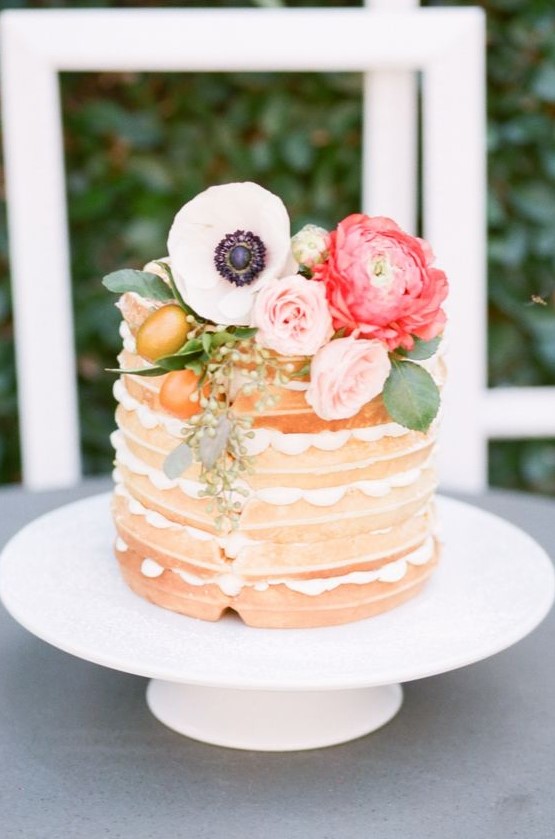 a small yet cute waffle wedding cake with pink and coral blooms, foliage and kumquats for a spring wedding