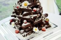 a stack of brownies decorated with chamomiles, fresh strawberries and hearts is a cool rustic wedding idea that loosk super cute