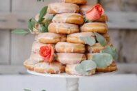 a stack of glazed donuts topped with foliage and fresh roses is a gorgeous idea for a relaxed and fun wedding