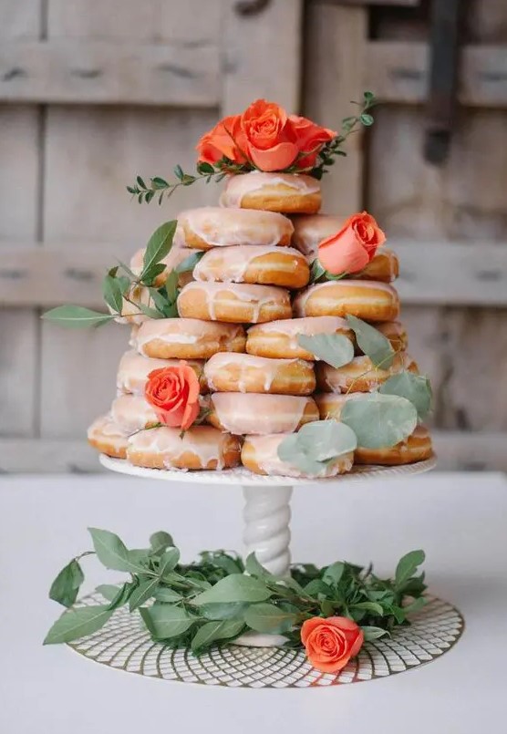 a stack of glazed donuts topped with foliage and fresh roses is a gorgeous idea for a relaxed and fun wedding