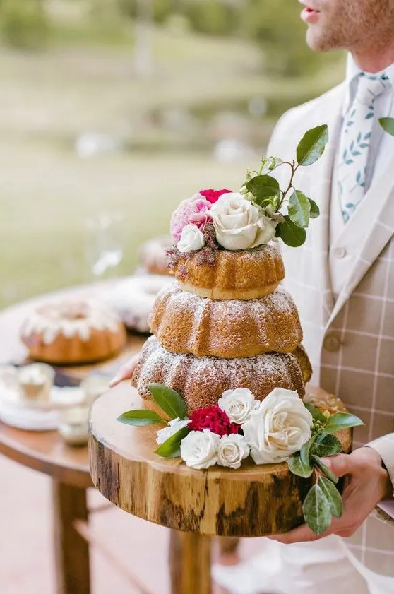 a three-tier bundt cake cake with white and pink blooms and greenery is a very pretty idea