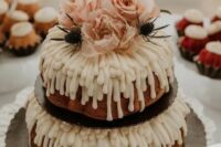 a two-tier bundt wedding cake with creamy drip, blush blooms and thistles on top is a stunning idea for spring or summer