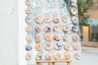 a wedding donut wall with purple marble donuts, with purple blooms and greenery is a super trendy and edgy idea