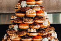 a whole tower of delicious caramel and chocolate donuts with a calligraphy topper and white blooms is wow