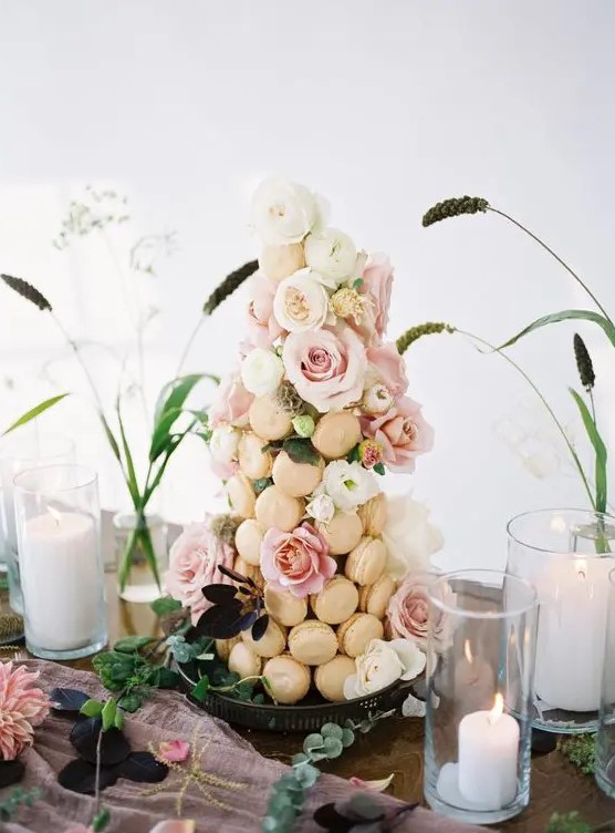 an exquisite macaron tower with neutral macarons and blush and white blooms and greenery is a very cool solution