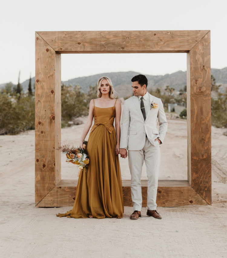 a mustard modern wedding dress with spaghetti straps, a pleated skirt and a tied waistline plus a cutout back