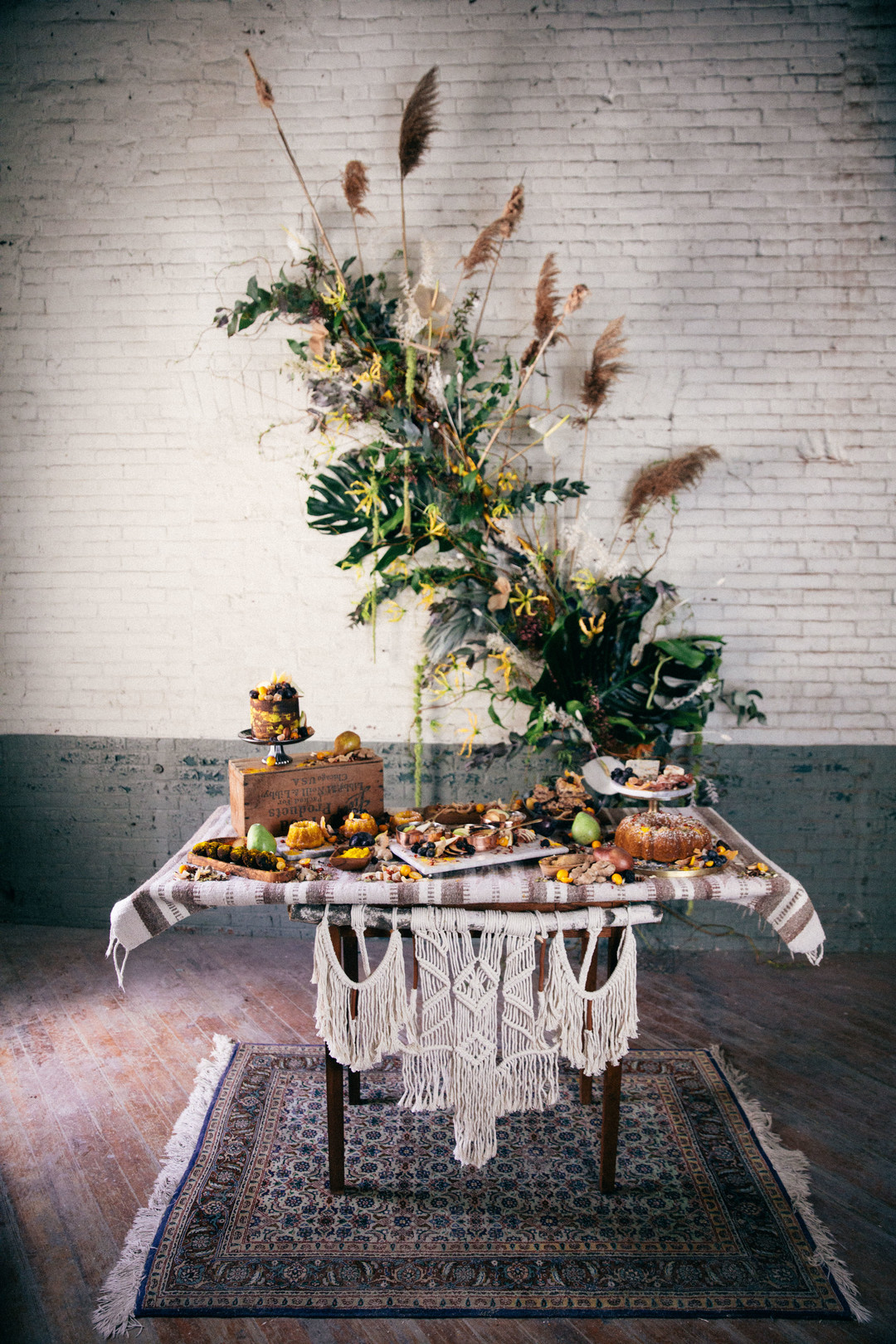 The table was decorated with macrame and there is a gorgeous lush greenery and dried flowers backdrop