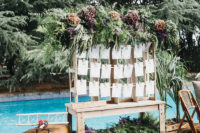 10 The wedding seating chart was done with lush greenery, dried blooms and a stack of vintage suitcases