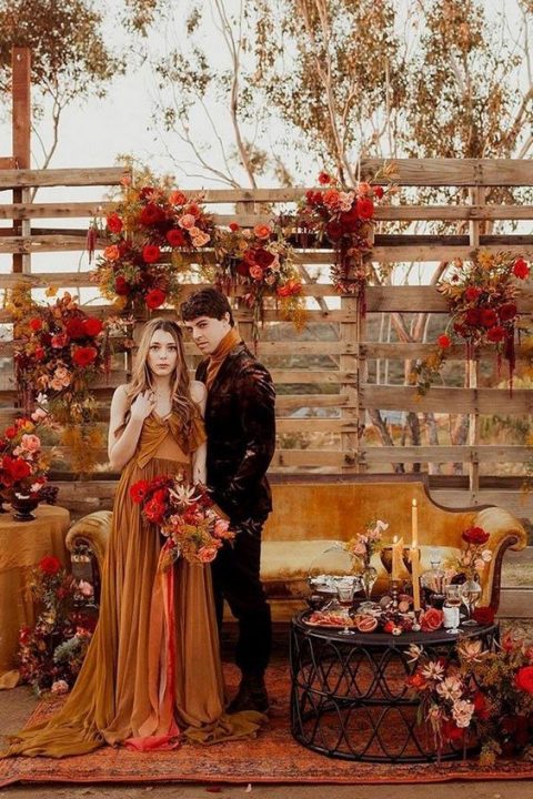 a rust colored wedding dress with a tied bow bodice, a pleated skirt and a train for a fall boho bride