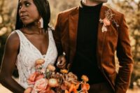 a black turtleneck, brown pants, an orange velvet blazer and a bold floral and drid foliage boutonniere for a fall boho wedding