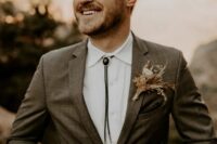 a boho groom’s look with a brown plaid pantsuit, a white shirt, a bolo tie is a lovely idea for a boho wedding