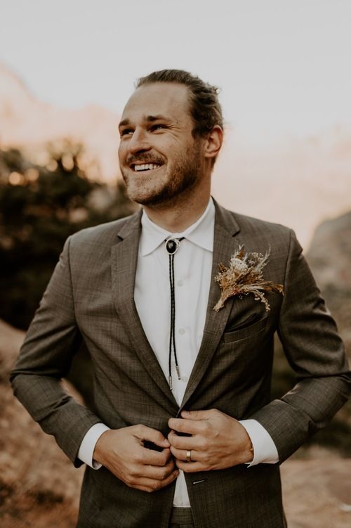 a boho groom's look with a brown plaid pantsuit, a white shirt, a bolo tie is a lovely idea for a boho wedding