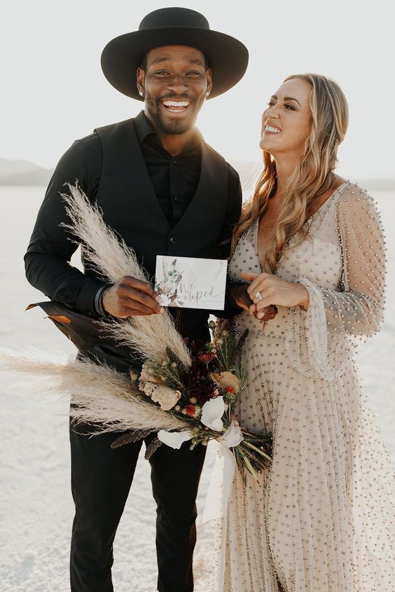 a bold boho groom's look with a black shirt, black pants and a waistcoat, a black hat is a very cool and stylish idea to rock