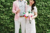 a bright summer groom’s look with a floral shirt, a pink jacket, neutral pants, brown moccasins and a belt