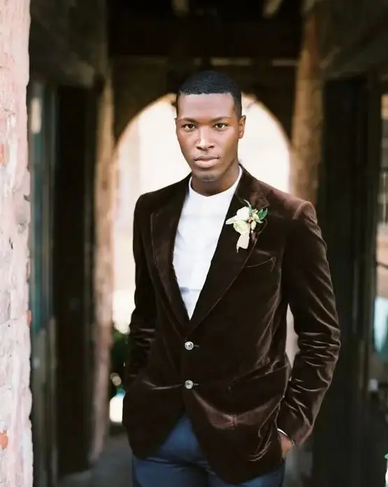 a casual groom's look with navy pants, a white shirt and a brown velvet blazer for a modern wedding