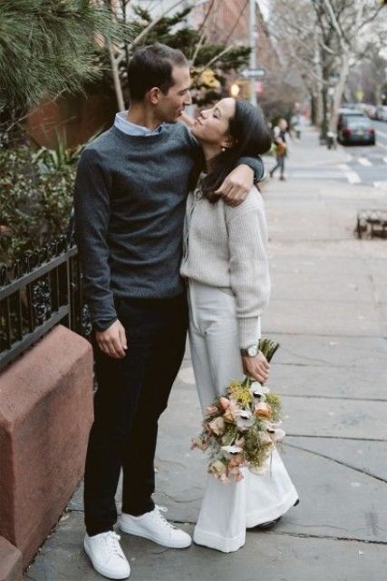 a casual groom's outfit with a blue shirt, grey sweater, black pants and white sneakers is a cool idea for a city hall wedding