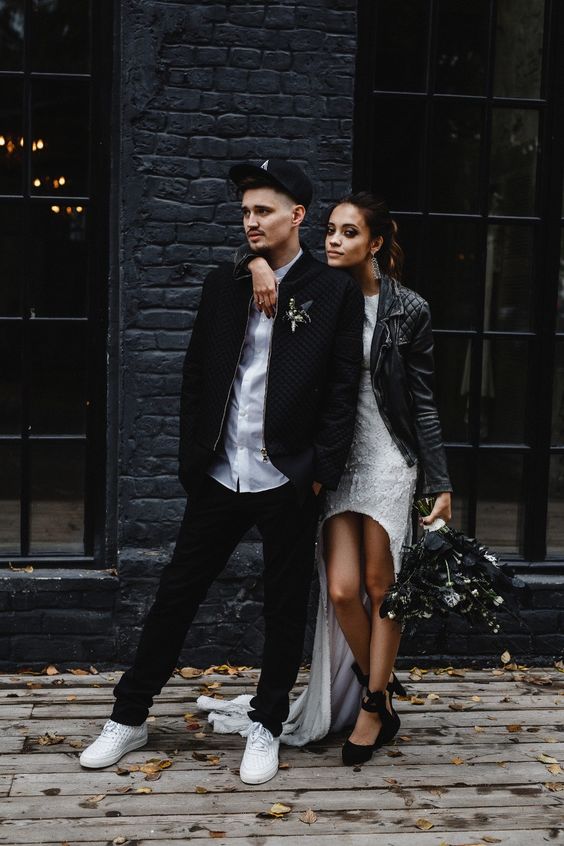 a casual groom's outfit with a white shirt, black pants, a black jacket and white sneakers plus a cap on top