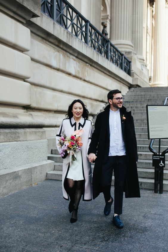 a casual groom's outfit with a white shirt, black pants, a midi coat and black shoes is a lovely idea for a city hall wedding