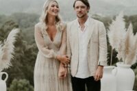 a contrasting boho groom’s look with a white shirt and a neutral linen blazer, black pants, black shoes is a cool idea for a hot day