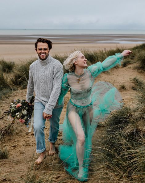a grey patterned sweater and blue cuffed jeans for a super informal and fun coastal wedding in a cold season