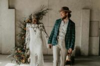 a lovely boho groom’s look with a printed shirt, grey pants, a teal windowpane blazer, brown shoes and a tan hat