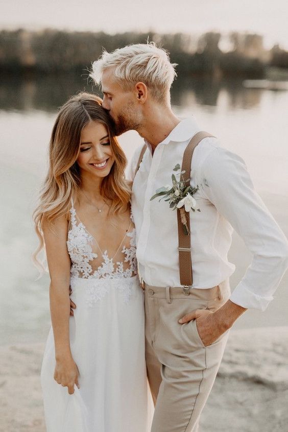 a lovely neutral groom's look with a white shirt, grey pants, beige suspenders and a boutonniere is a cool idea for a boho wedding