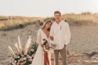 a pretty boho groom’s look with an oversized white shirt, grey pants, black shoes and a boutonniere is a cool and easy to repeat outfit