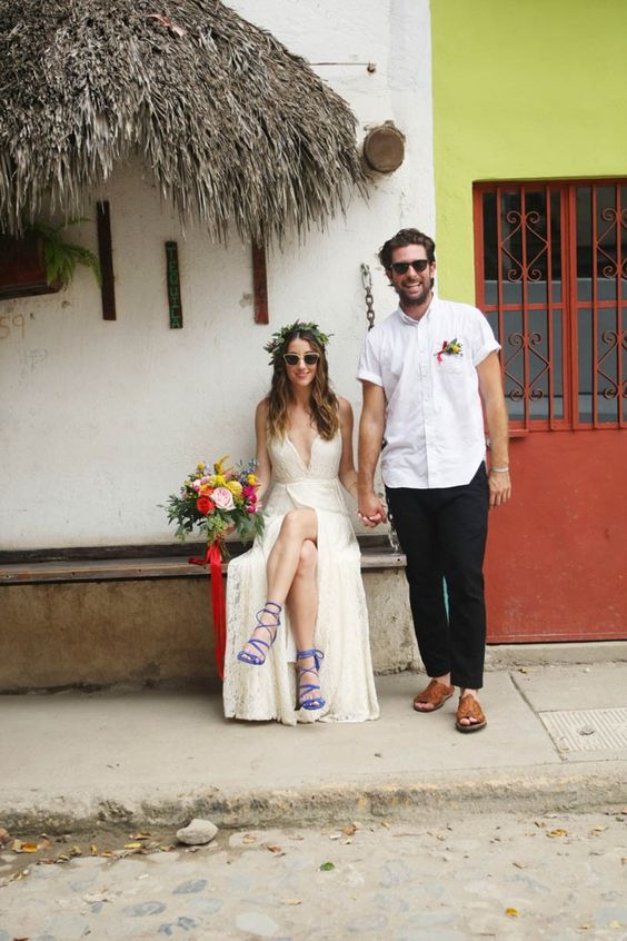 A relaxed tropical wedding groom's look with a white short sleeve shirt, black pants, tan sandals and a boutonniere