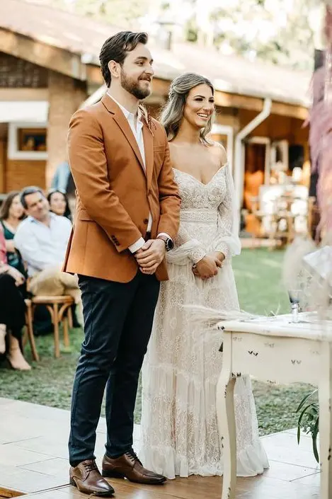 A simple and stylish look with a white shirt, a rust colored blazer, navy pants, brown shoes and a watch for a boho wedding