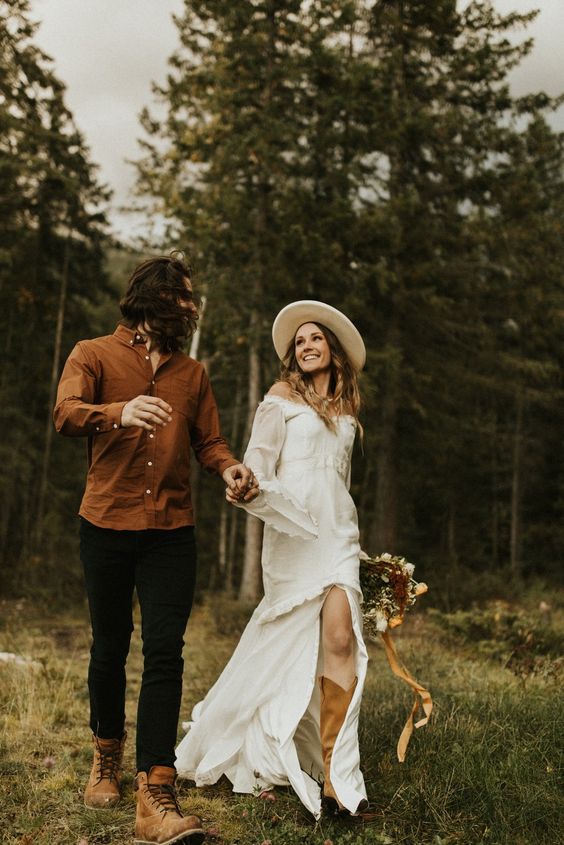 A simple boho groom outfit with a rust colored shirt, black pants and rust colored boots that are a great idea for a fall wedding