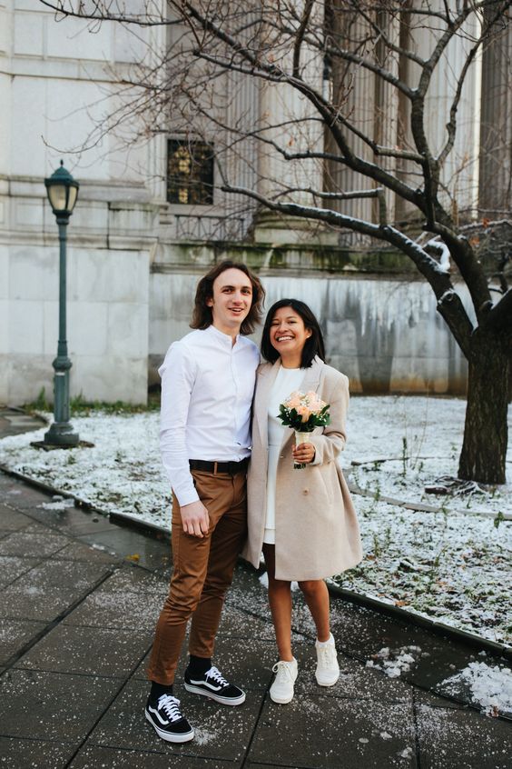 A super simple and casual groom's look with a white shirt, rust colored pants, black sneakers and socks for a city hall wedding