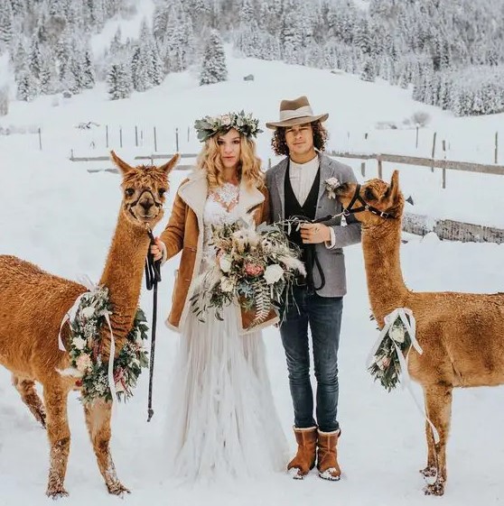 a winter boho groom wearing blue jeans, a white shirt, a black waistcoat, a grey blazer, brown boots and a hat